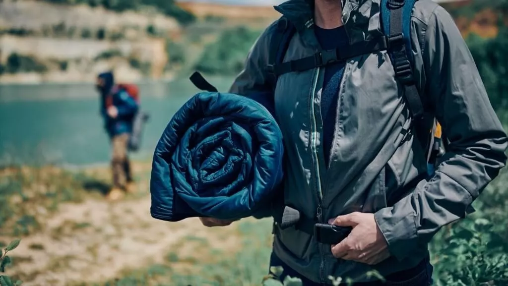 man carrying a folded sleeping bag