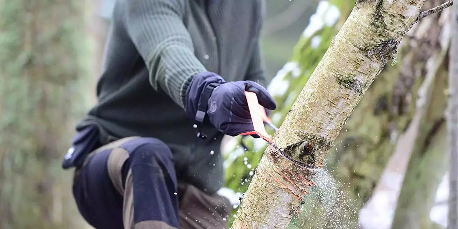 image of man using a manual pocket chainsaw cutting tree branch