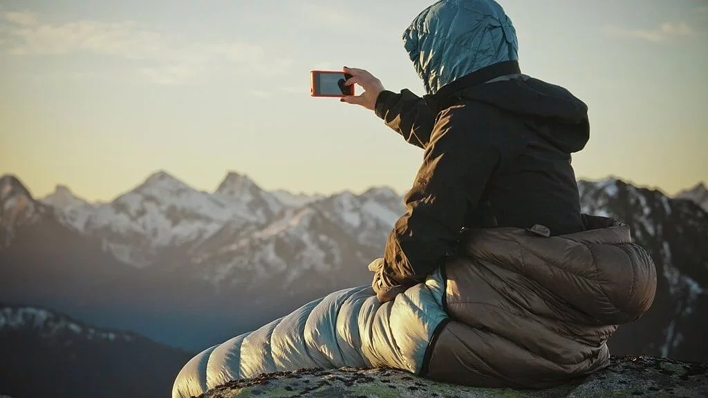 a lady in a mummy sleeping bag taking selfie