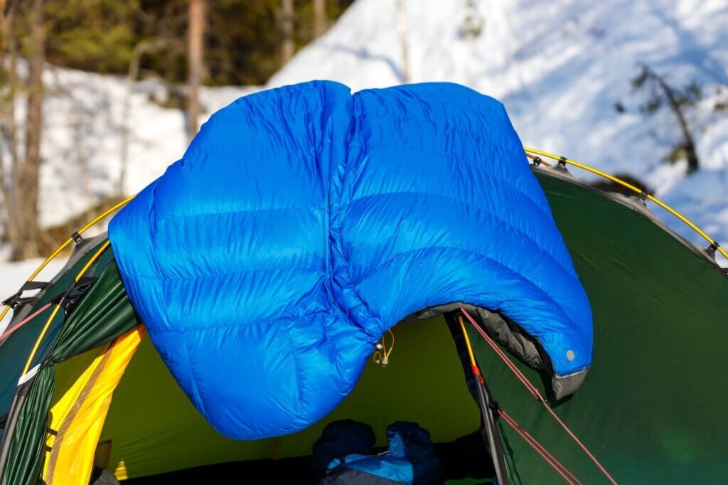 a blue sleeping bag aired on top of a tent
