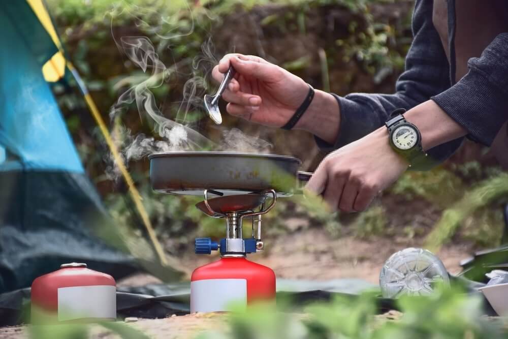 a woman cooking on a camping pan cookware
