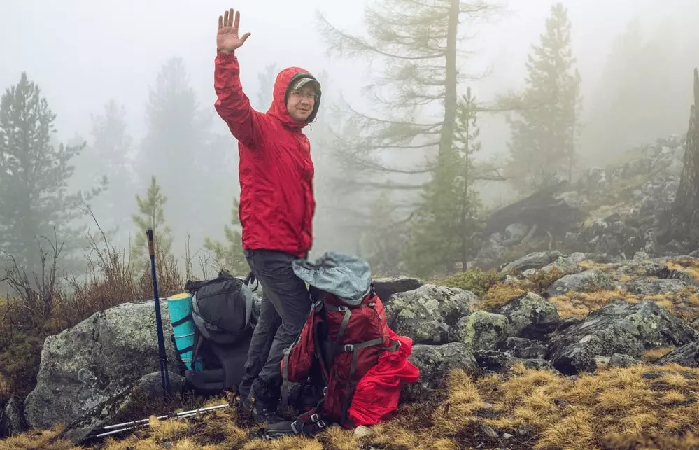 camper with packed backpacks waving goodbye