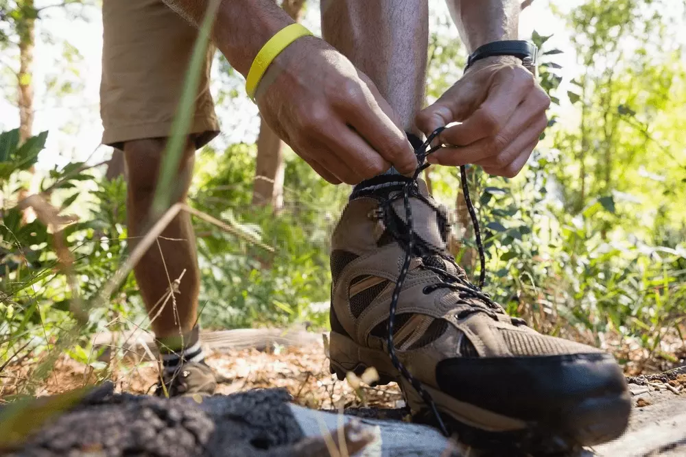 man fitting on a hiking boot on the trails