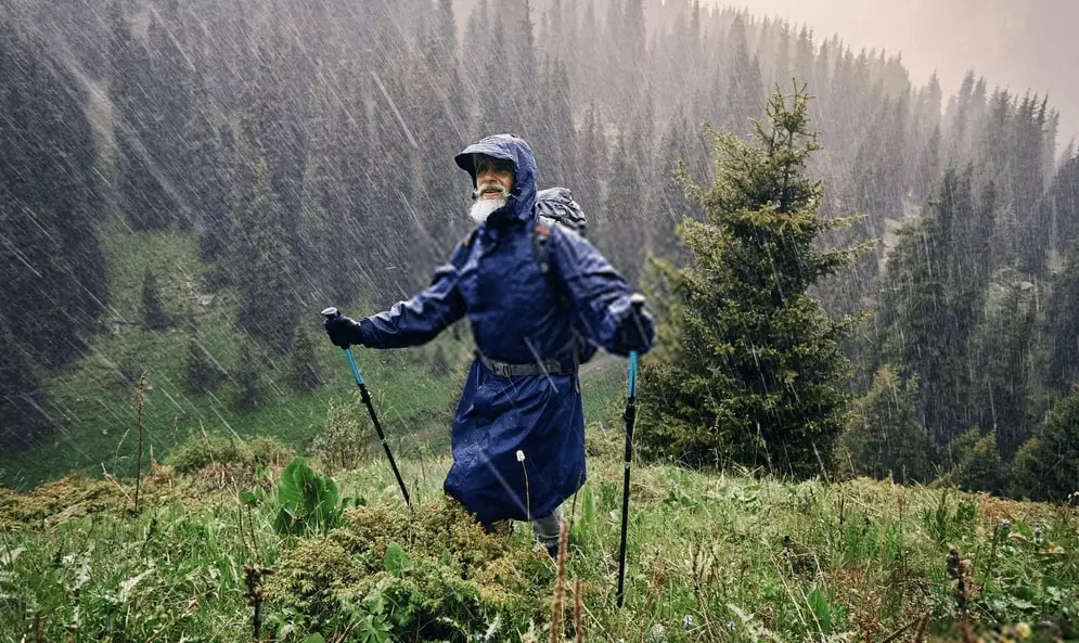 man with a raincoat on hiking in the rain