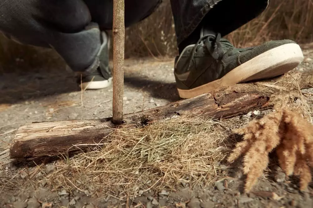 man makes fire with sticks