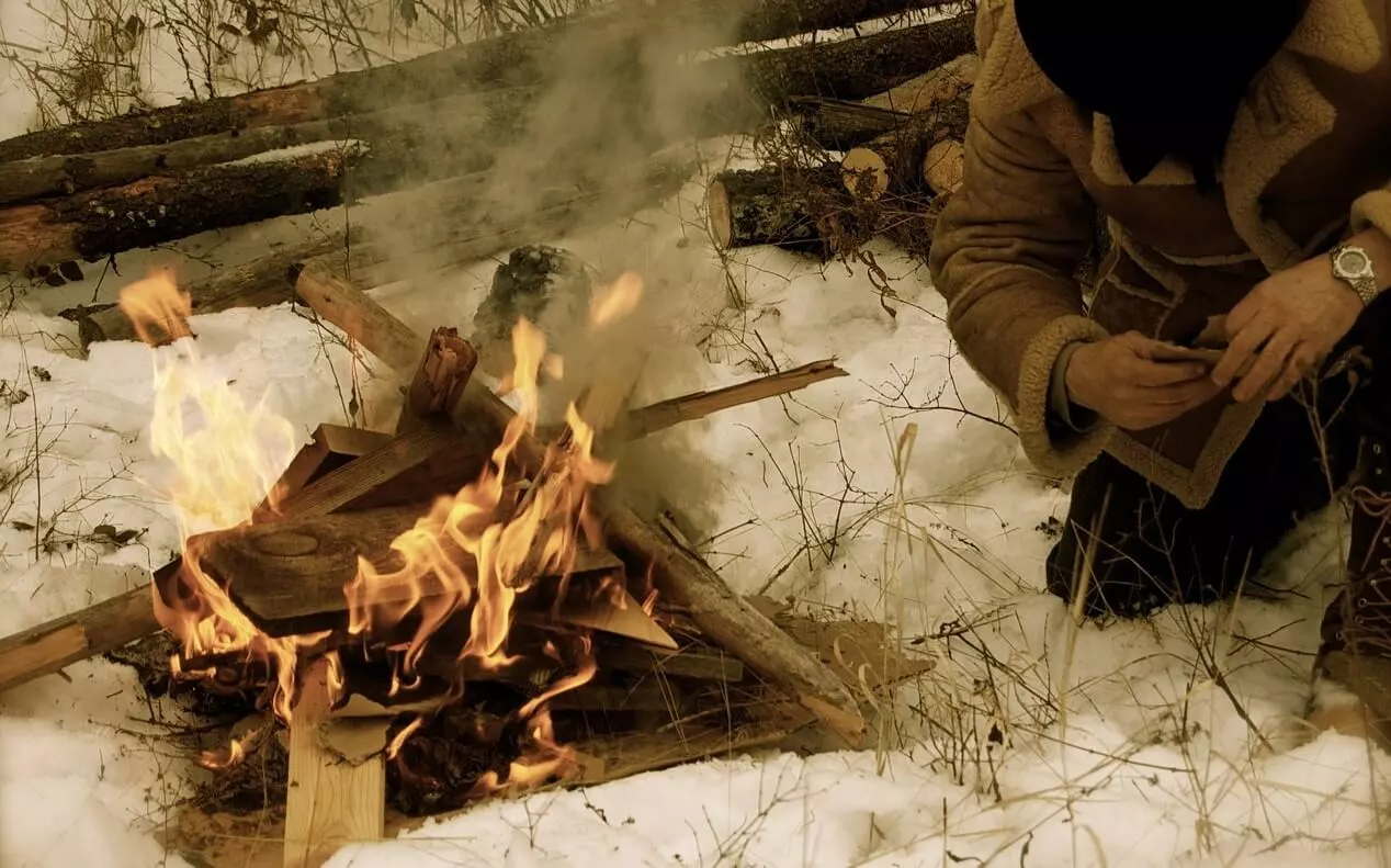 mountain man lighting up a campfire