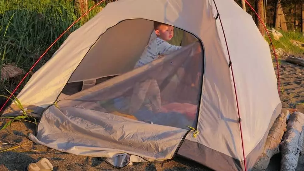 image of toddler inside tent looking at the zippers on the tent door