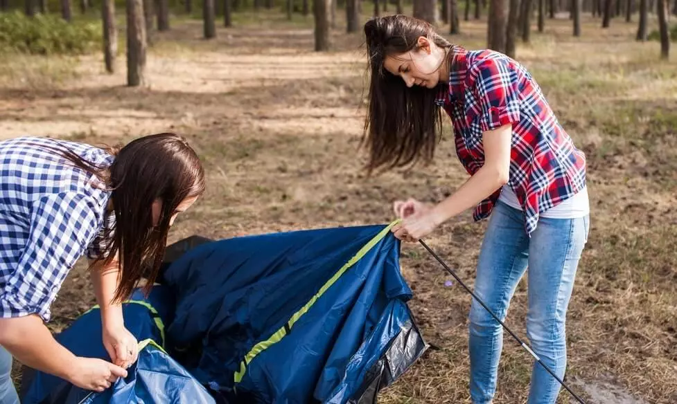 image of two women taking down a tent preparing for packing