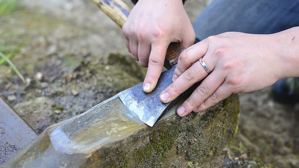 sharpening an axe using a stone