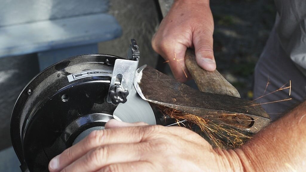 sharpening an axe using an electric grinding stone