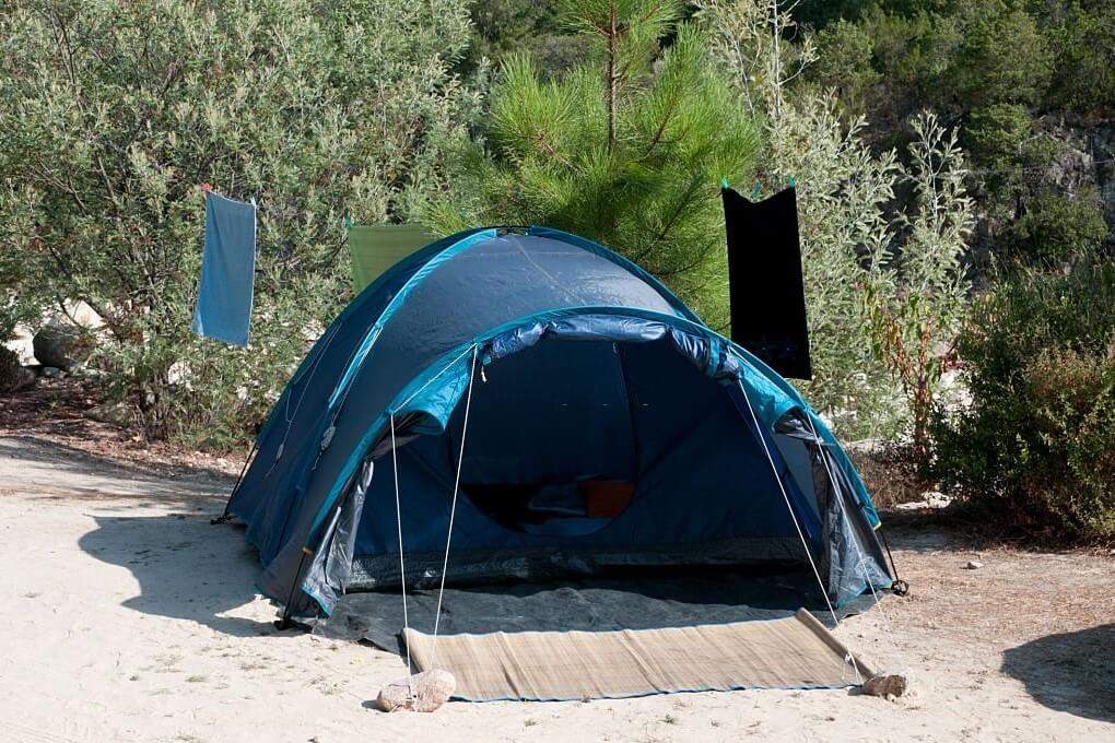 tent pitched on sand using improvised stone anchors
