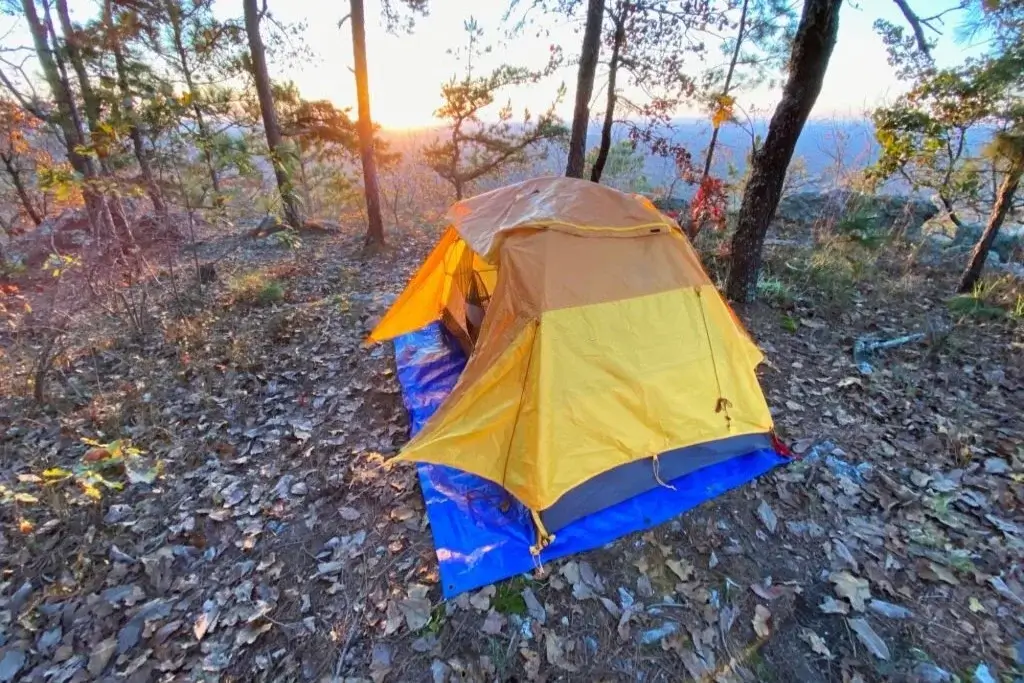 an orange tent set up on a blue tarpaulin