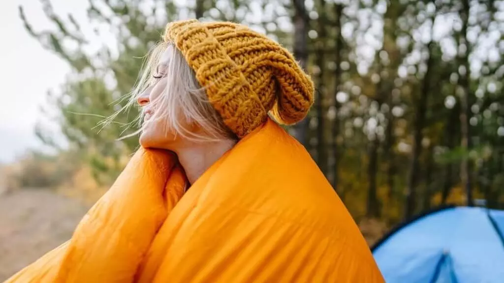 woman wrapped up in a down camping blanket