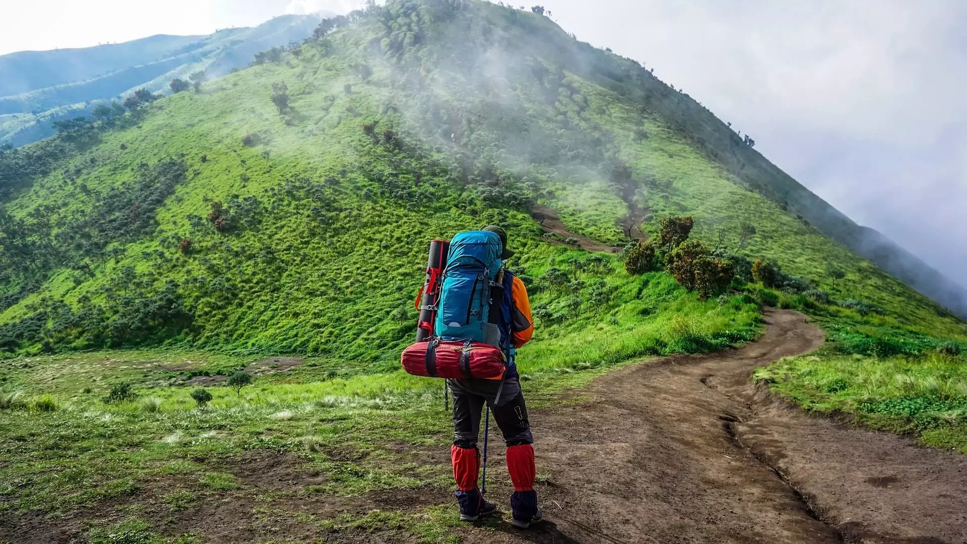 male walking trail carrying backpack