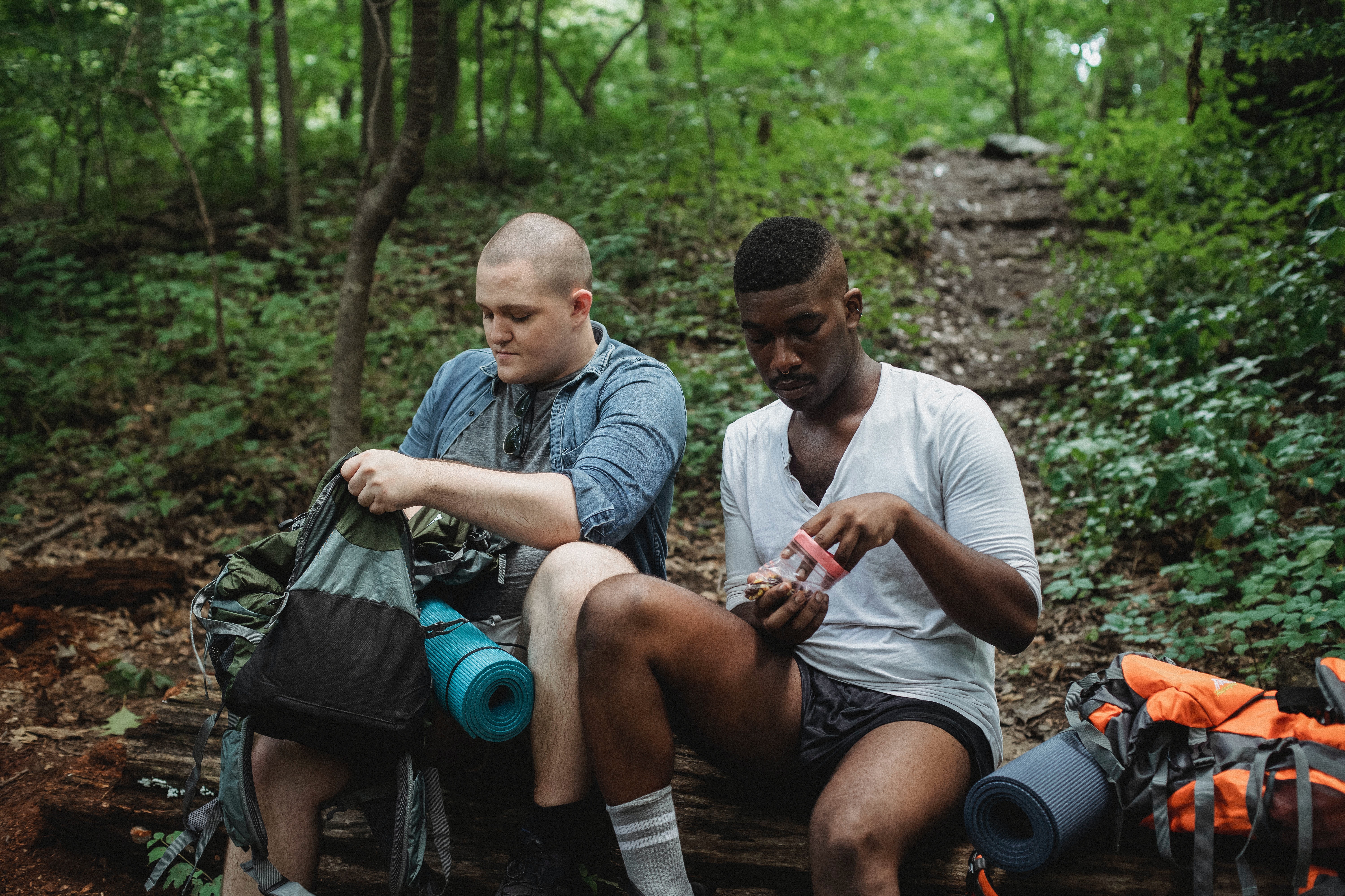 image of two men sitting on trail eating snacks