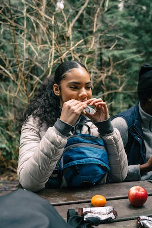 image of a woman snacking seated with backpack on