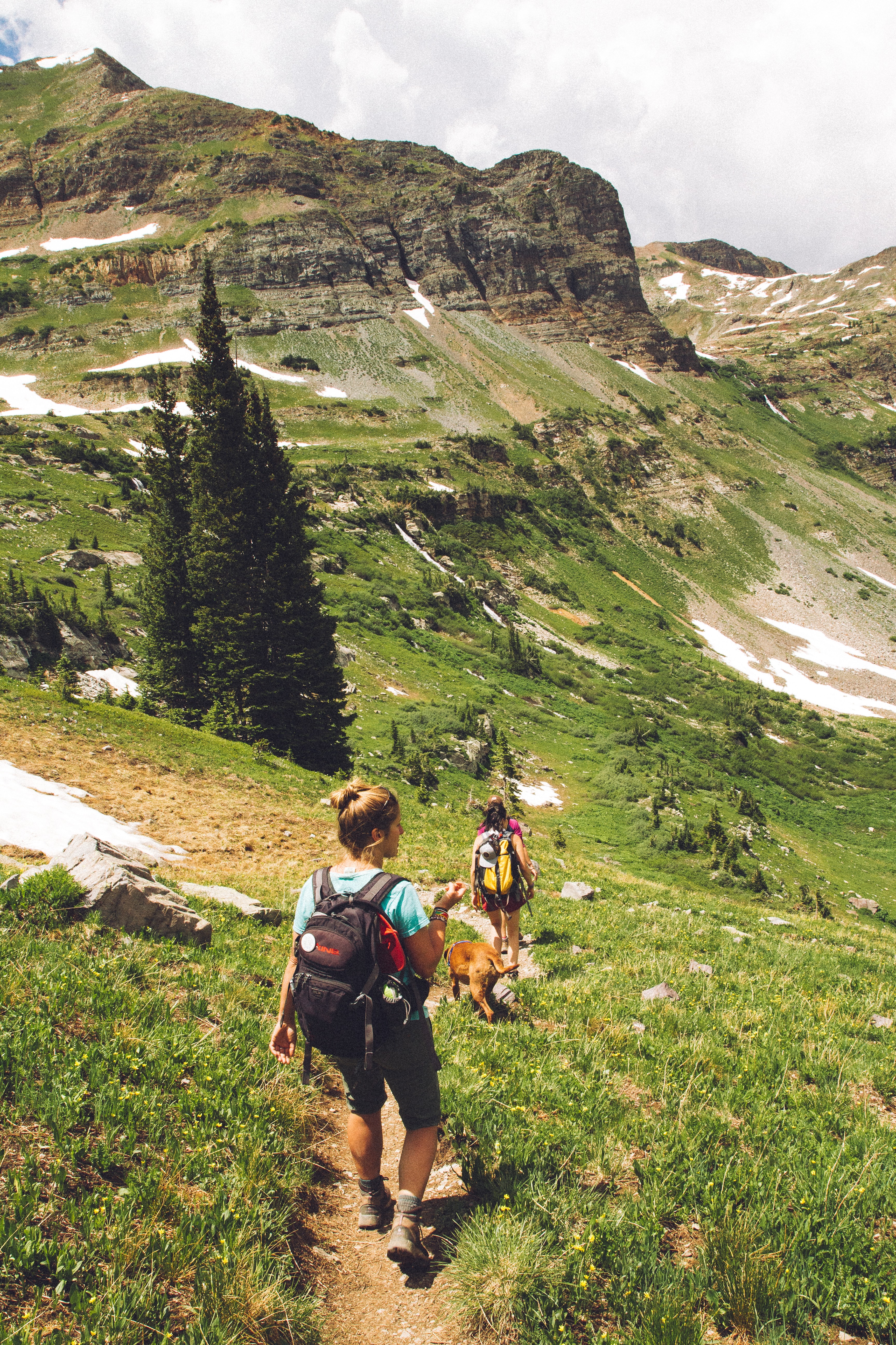 image of two women hiking on trail along mountains